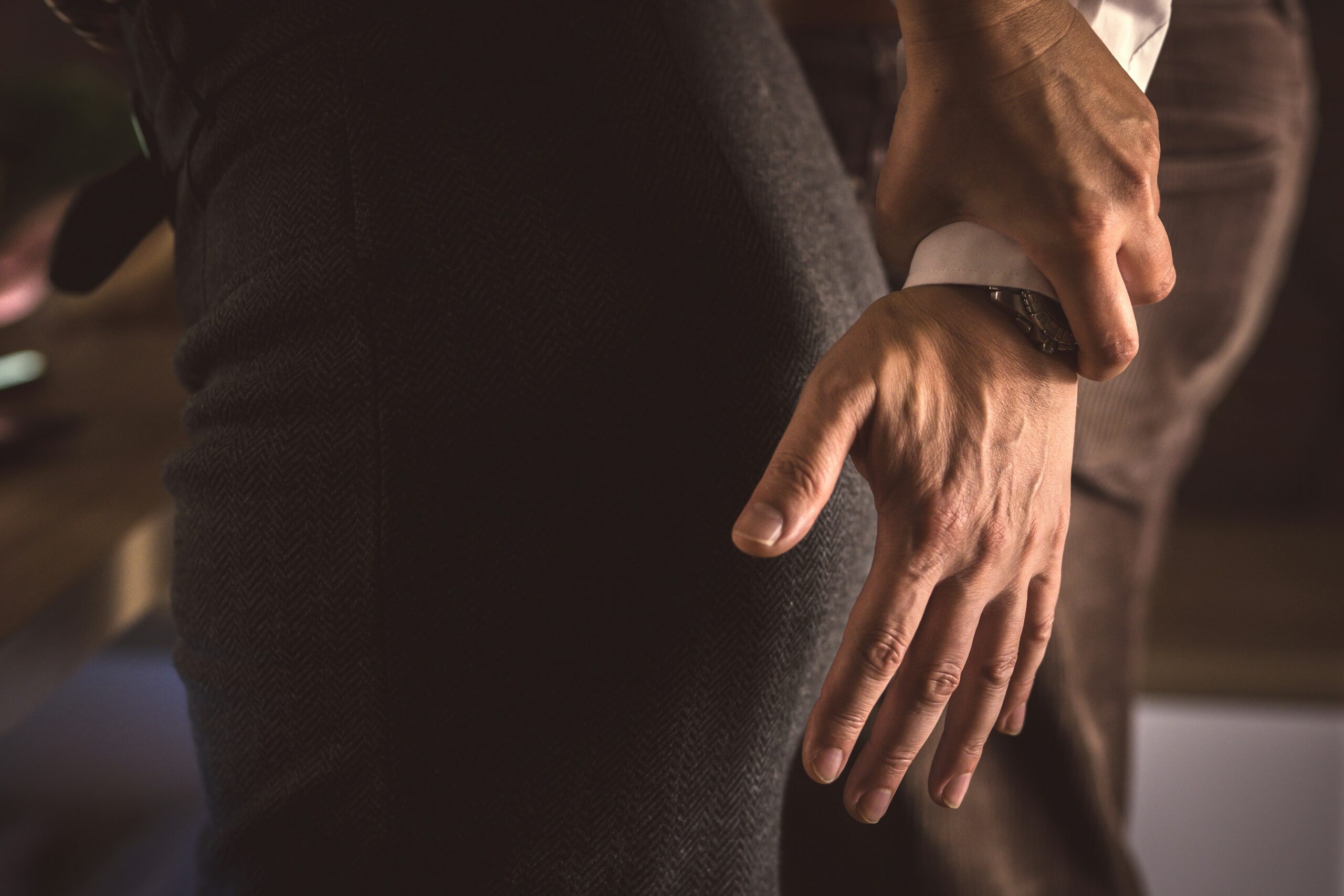 Close-up of a person grabbing another’s wrist in an office setting, conveying an unwanted or inappropriate physical interaction that suggests workplace harassment.