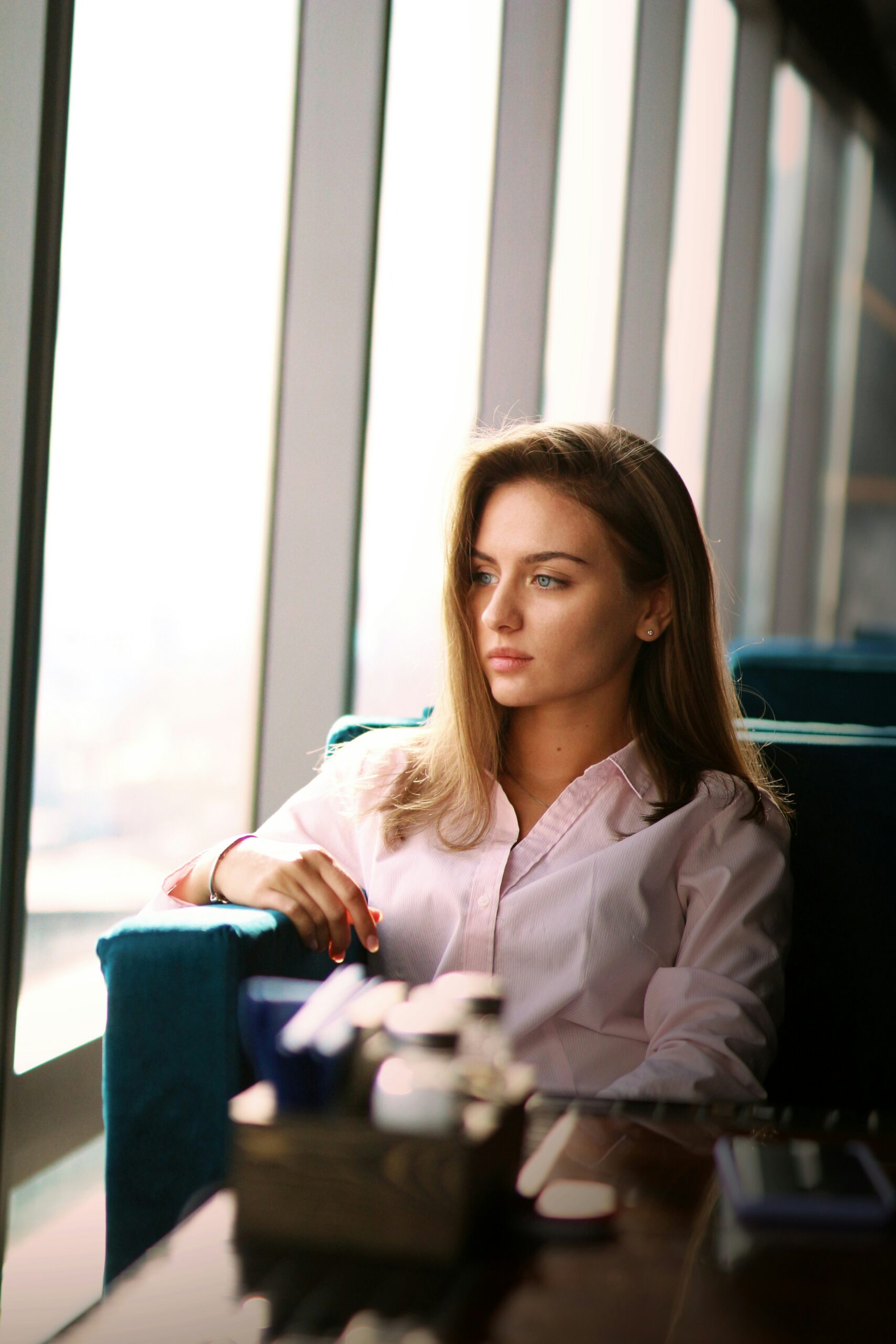 A woman sitting in a chair, gazing out of a window with a scenic view.